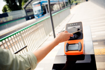 Woman using contactless payment method for travel on urban public transport in daylight setting