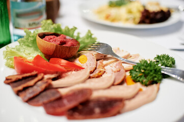 Assorted Meat Platter with Vegetables and Dip on a Gourmet White Plate..