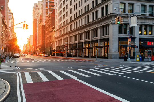 Empty cityscape with no people at the intersection of 5th Avenue and 23rd St in New York City with sunlight shining between the background buildings