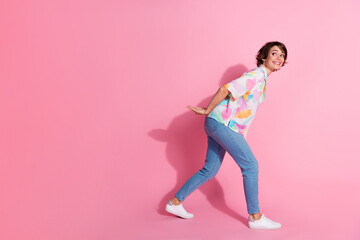 Full size photo of pretty young lady arms carry empty space wear shirt isolated on pink color...