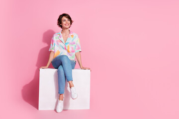 Full size photo of pretty young lady sit cube look empty space wear shirt isolated on pink color...
