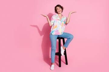Full size photo of pretty young lady sit stool hold empty space wear shirt isolated on pink color...