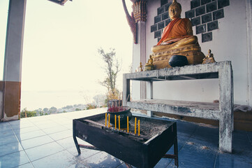 Golden Buddha Statue in Outdoor Setting With Incense and Offerings..