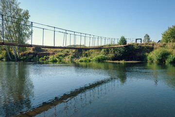 Suspension bridge across the river on a sunny summer day.