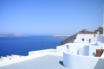 Fototapeta premium Coastline of Santorini with Oia village in the far distance and traditional building in the foreground