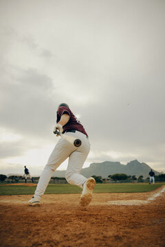 Base runner making a sprint for a triple in a scenic baseball stadium with dramatic skies