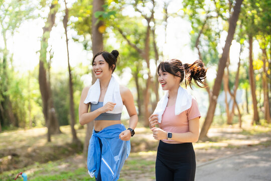 Women and friend jogging together in the park for good health and a strong body for teamwork in the morning. Women are training, exercising or running in the park with support, smiles and happiness.