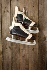 Old ice hockey skates hanging on a weathered wooden wall