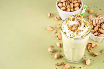 Pistachio milkshake, healthy diet protein cocktail, non-dairy whipped shake with vegan pistachio milk, whipped plant-based cream, sprinkled with nuts, on light green background