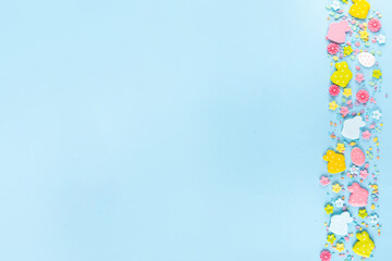 Easter sweets and candies background. High-colored blue flat lay with various Easter chocolate eggs, treats, symbols of easter sheep, bunny, carrot, flowers, cookies, top view copy space, frame
