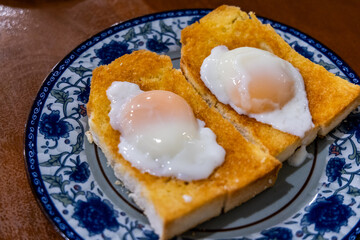 Close up on roti bakar telur goyang or toast bread with half boiled eggs, popular breakfast delicacy in Ipoh, Perak, Malaysia