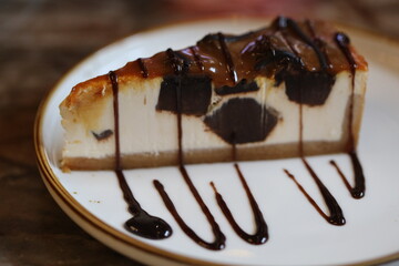 A slice of cheesecake served with a rich chocolate sauce on a plate, perfect for dessert or snack.