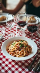 Savor the Flavors: A Delicious Plate of Spaghetti with Red Wine on a Checkered Tablecloth - A Culinary Masterpiece for Food Lovers and Fine Dining Enthusiasts