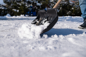 black shovel removing snow from the sidewalk