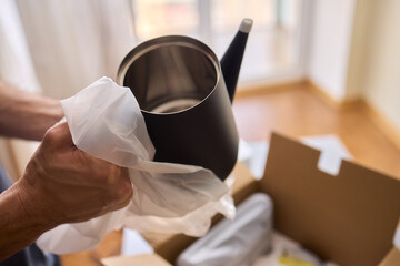 Unboxing a stylish, modern black kettle designed for use in a bright, contemporary kitchen space
