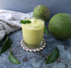 glass with avocado smoothie and fruits around and rustic background