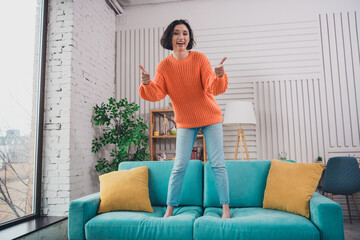 Obraz premium Young woman in orange sweater enjoying at home in a modern living space