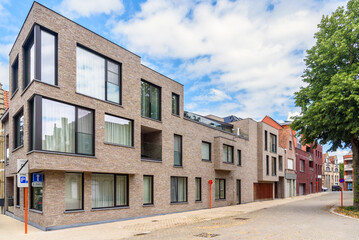 Modern brick town houses a along a street in a city centre under partly cloudy sky in summer