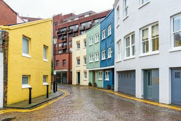 Pastel coloured town houses along a narrow cobbled street in London on a rainy winter day