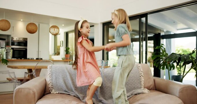 Happy girls, siblings and jumping with sofa for fun day, bonding or playful energy together at home. Excited, children or kids playing with smile or holding hands on couch for holiday or weekend