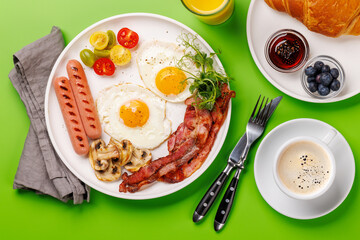 A classic breakfast plate featuring sunny-side-up eggs, crispy bacon, sausages, and fresh tomatoes