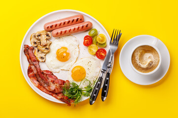 A classic breakfast plate featuring sunny-side-up eggs, crispy bacon, sausages, and fresh tomatoes