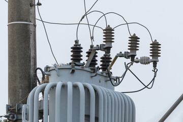 Close up on a power transformer attached to an urban power and lighting pole.