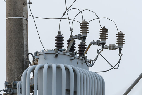 Close up on a power transformer attached to an urban power and lighting pole.