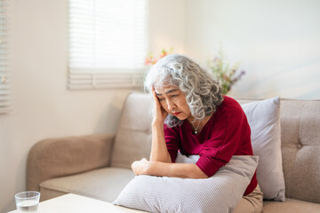 Unhappy Retired Senior Woman holding her head with pain expression . Face of senior woman suffering...