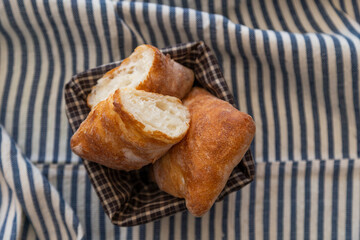 A basket of freshly baked artisan bread with a golden crispy crust and airy interior, placed on a...
