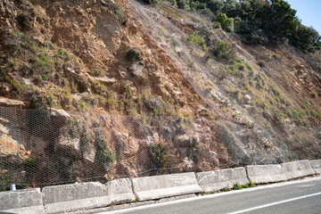 mountain road along the Adriatic Sea, rocky slopes are reinforced with a metal mesh to prevent...