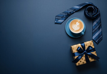 Father's Day flat lay with a tie, coffee, and present on a dark blue background