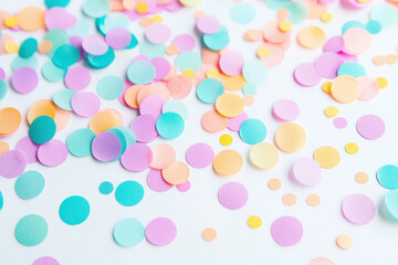 Colorful confetti in pastel shades scattered on a white surface, perfect for celebrations or festive events.