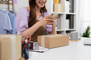 A young woman uses her phone to check the code of a parcel on her desk.