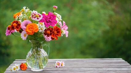Vibrant Bouquet of Mixed Flowers in a Glass Vase on a Wooden Table