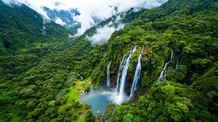 Fototapeta premium Majestic Waterfalls Cascading Over Lush Green Forest With A Vibrant Rainbow Below In A Tropical Paradise
