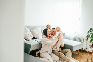 Beautiful happy young family with small children resting at home.