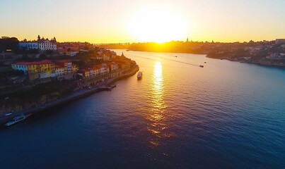 Fototapeta premium Golden sunset over a river with boats and colorful buildings along the shore.