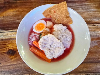Pink noodles soup with bouncy pork and shrimp balls soft-boiled eggsin pink soupserved in cup. Yentafo buffet is type of noodles. It's like fishball noodles but uses red soup from fermented bean curd.