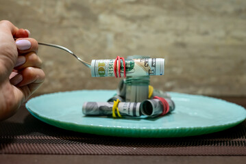Money spread out on a turquoise plate with a knife and fork nearby, food costs, price increases.