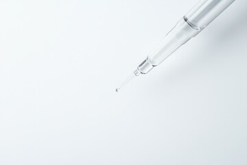 clean minimalistic pipette with single droplet hovering at its tip isolated on pristine white backdrop