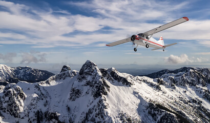 Fototapeta na wymiar Small Airplane Flying Over Snow-Covered Mountain Range Under Clear Sky