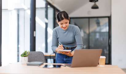 Beautiful young business asian woman standing while smiling looking at camera in the office