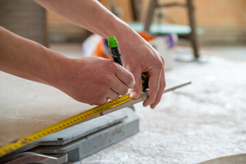 Focus sur un homme qui est en train de mesurer et faire apparaitre un repère sur son carreau de...