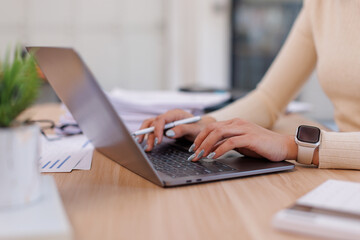 Close up Business Female using calculator and laptop for do math finance on wooden desk, tax,...