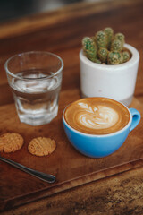 Hot Art Latte Coffee and Glass of Water on the Table, Coffee Shop Background, Warm Tone