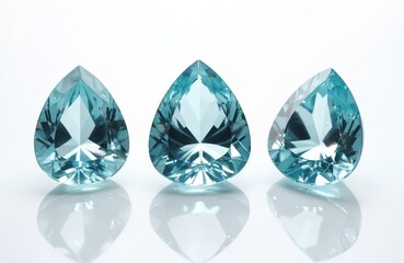 Macro photo of faceted transparent aquamarine gemstones. Stones teardrop shaped with shiny surface. Three precious gems isolated against white background reflecting light. Luxury wealth concept.
