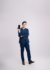 Full body image of Asian male businessman wearing a suit using phone and posing on a white...