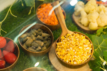 Wooden bowls with frozen corns seeds, brussels cabbage, carrot cubes and strawberry in fridge