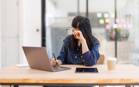 Portrait of tired young business Asian woman work with documents tax laptop computer in office. Sad, unhappy, Worried, Depression, or employee life stress concept